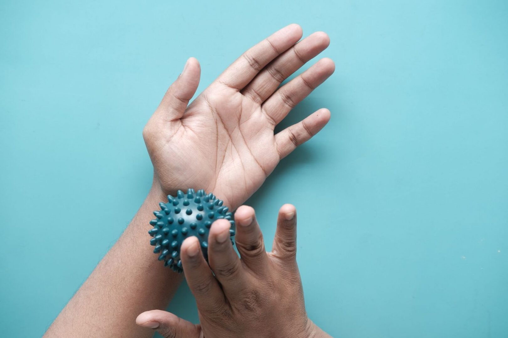Hand die een massagebal rolt tegen tintelende vingers