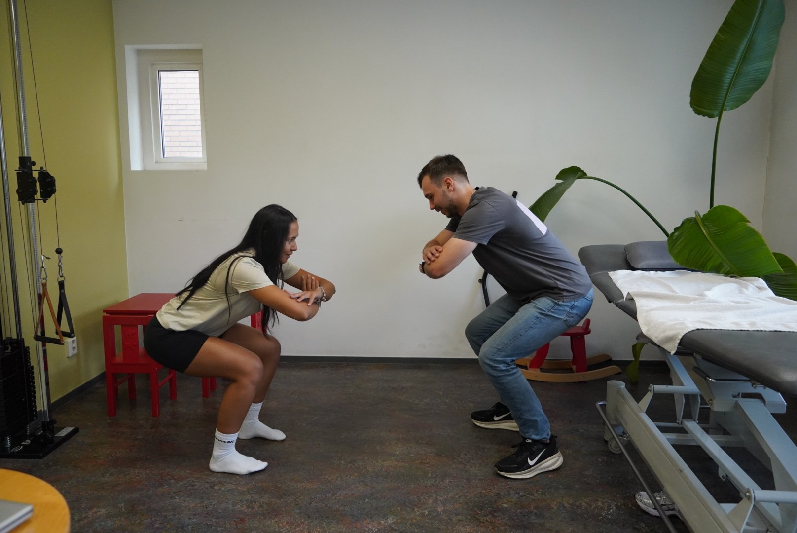 Fysiotherapeut en cliënt doen samen een squat