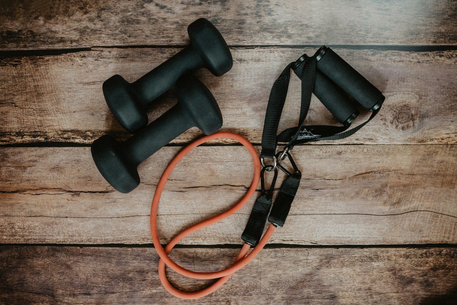 Dumbbells en een weerstandsband op een houten vloer