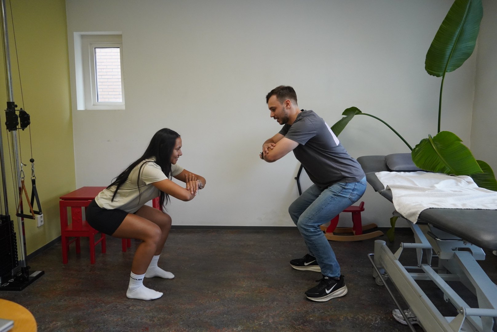 Fysiotherapeut en sporter doen samen een squat
